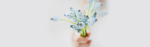 Hand giving bouquet of blue light blue flowers